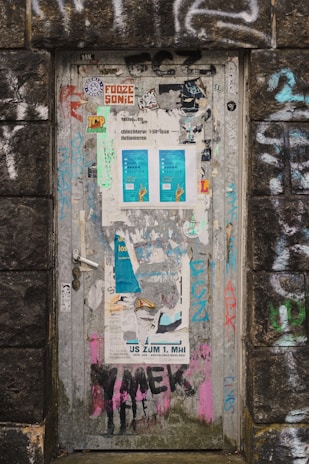 A weathered trailer door adorned with quirky signs and faded paint.