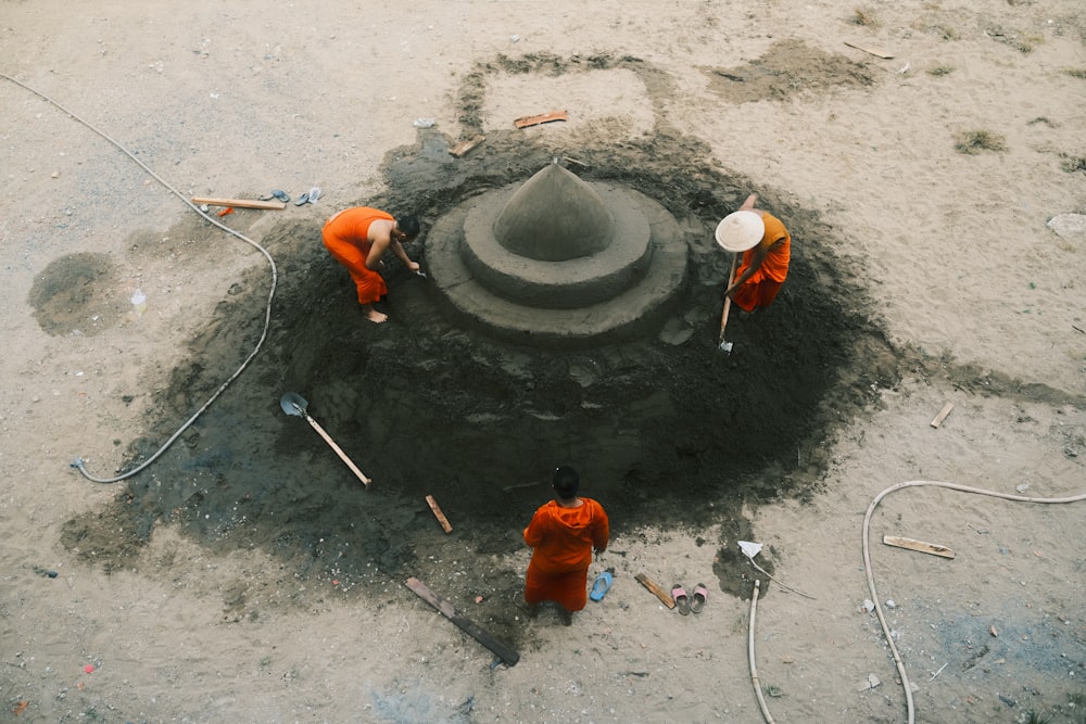 3 hombres con camisa naranja y pantalones naranjas parados sobre piso de concreto gris