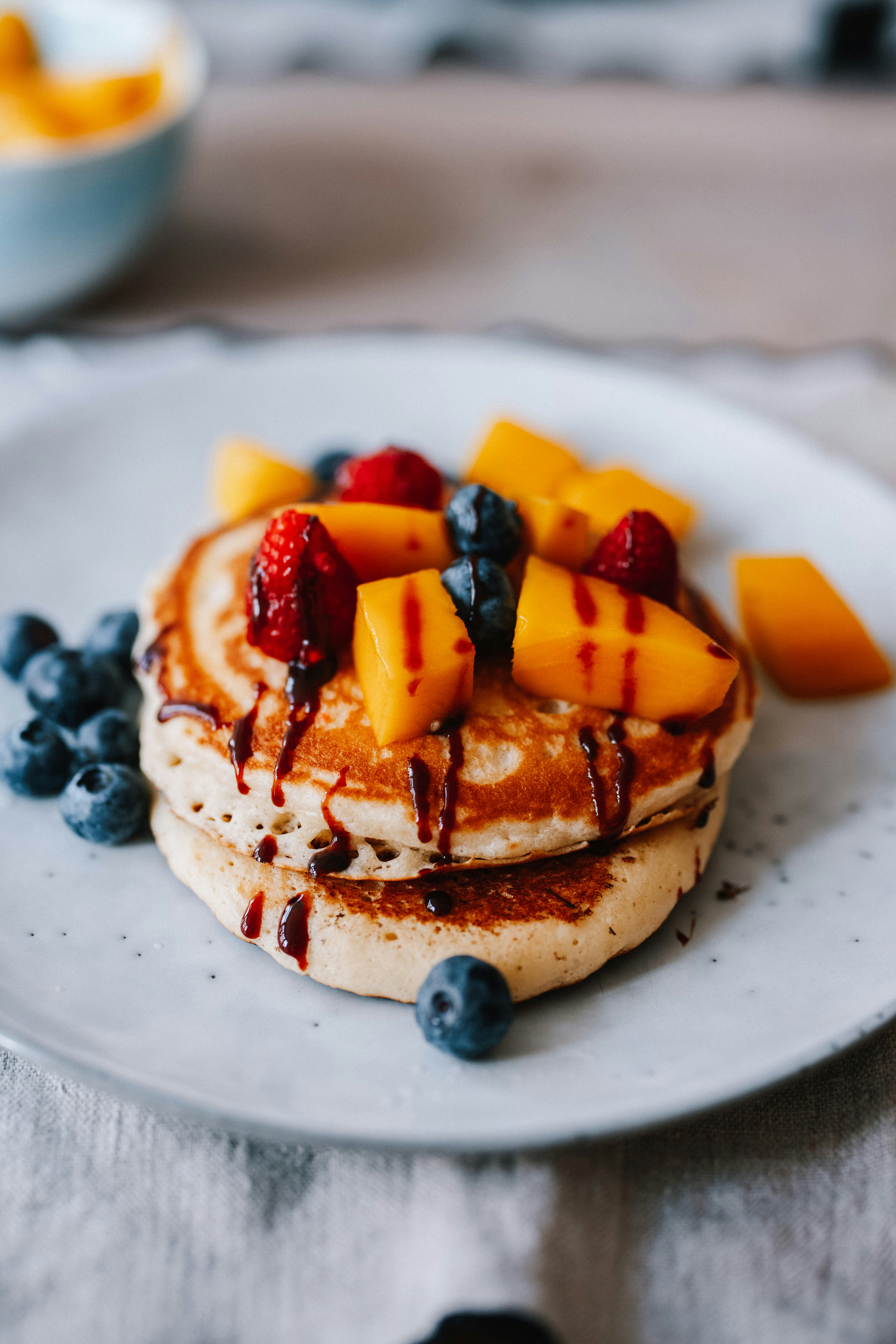 A stack of fluffy pancakes with syrup and fruits