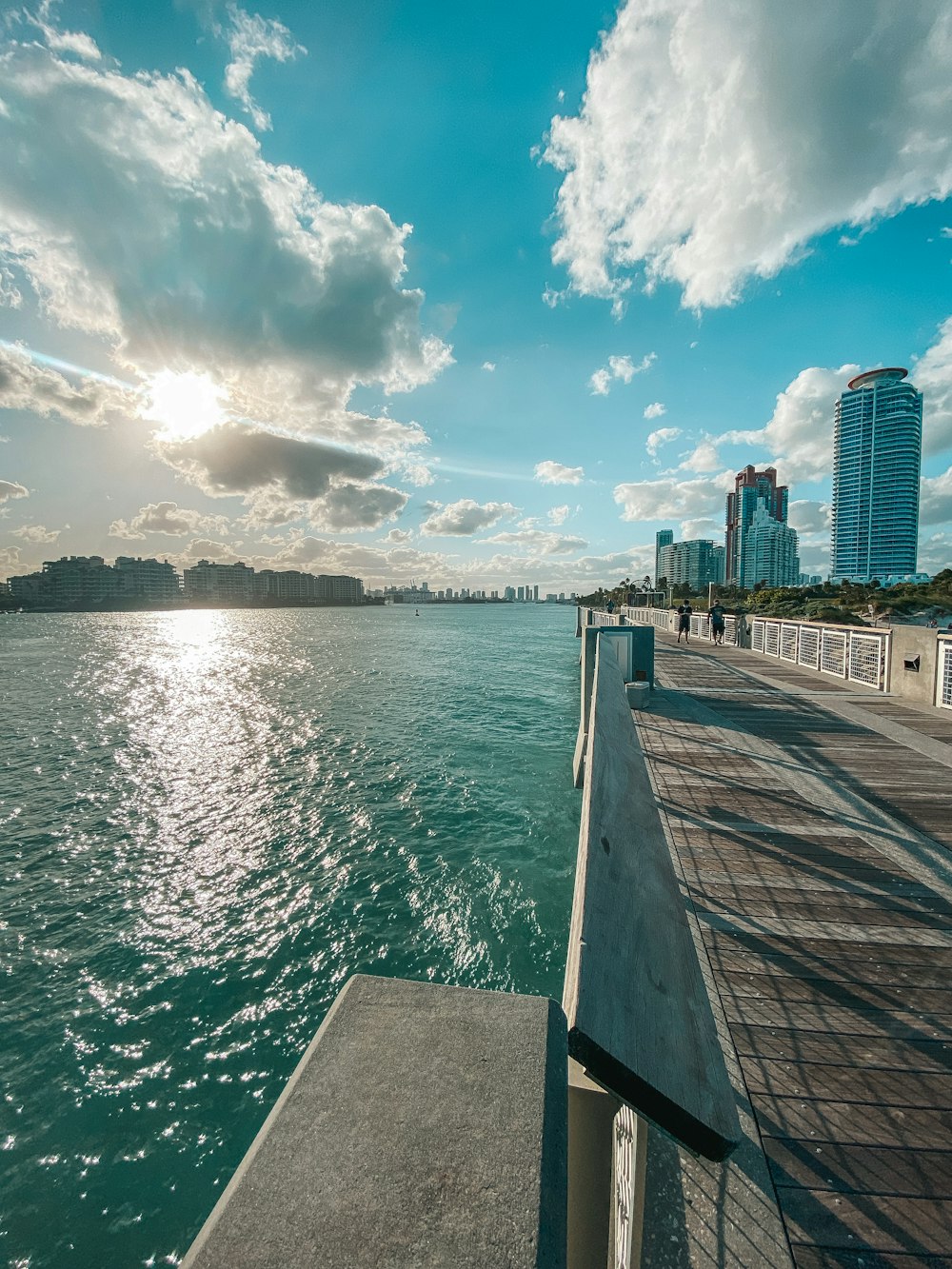 brown wooden dock near body of water under blue and white cloudy sky during daytime