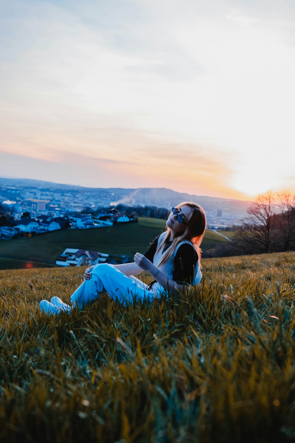 woman in white dress sitting on green grass field during daytime