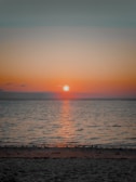 A picturesque sunset over a calm beach with gentle waves.
