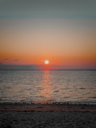 A picturesque sunset over a calm beach with gentle waves.
