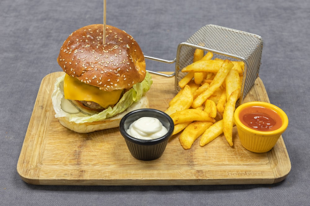 burger and fries on brown wooden chopping board