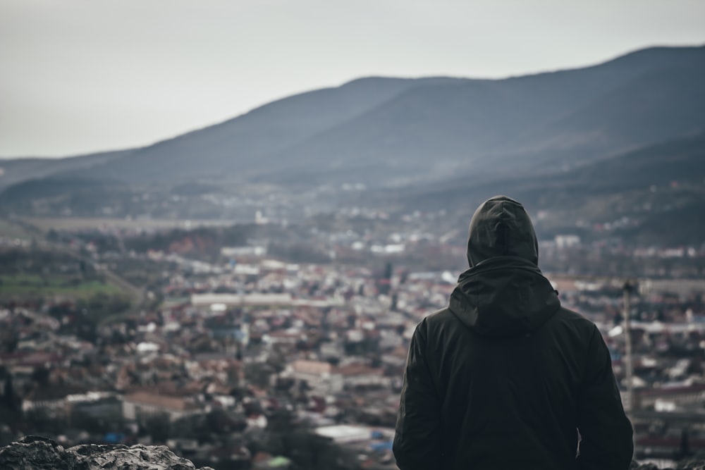 person in black hoodie standing on top of mountain during daytime
