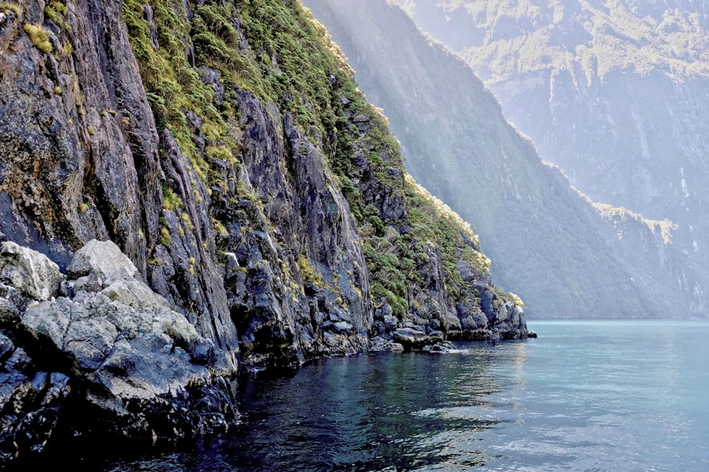 green and gray mountain beside body of water during daytime