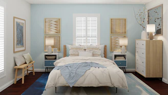 A modern bedroom with blue bed linens and soft lighting creating a relaxing atmosphere.