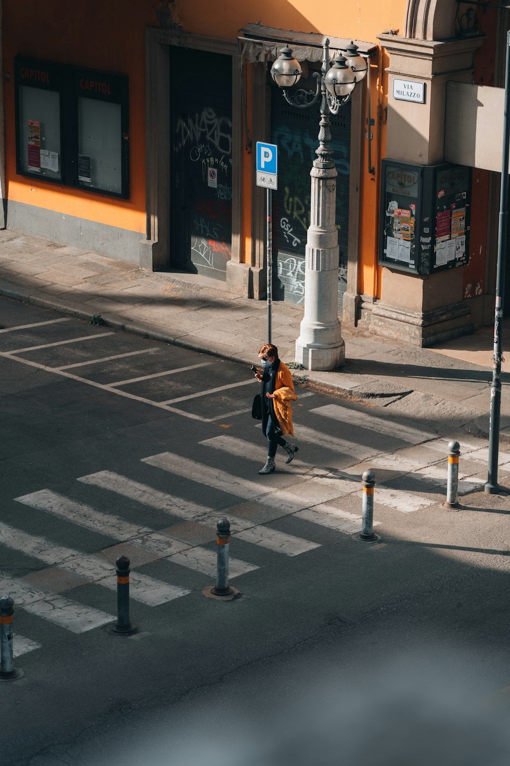 mulher na jaqueta preta andando na faixa de pedestres durante o dia