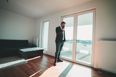 man in black suit standing near glass door