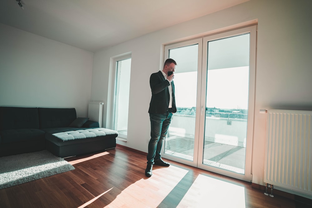 man in black suit standing near glass door