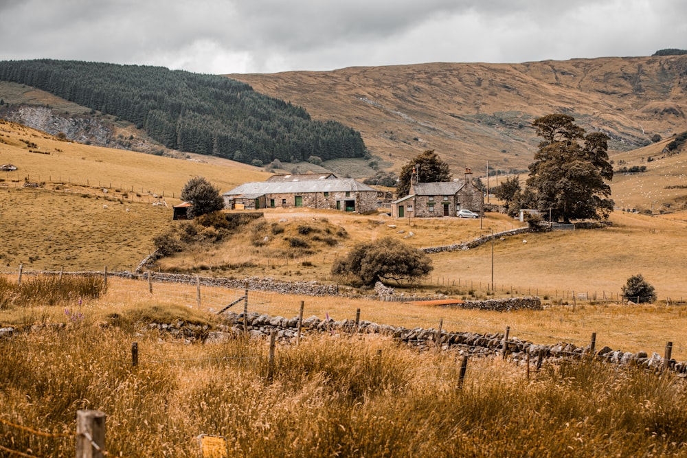 white and brown house near brown grass field and mountain during daytime