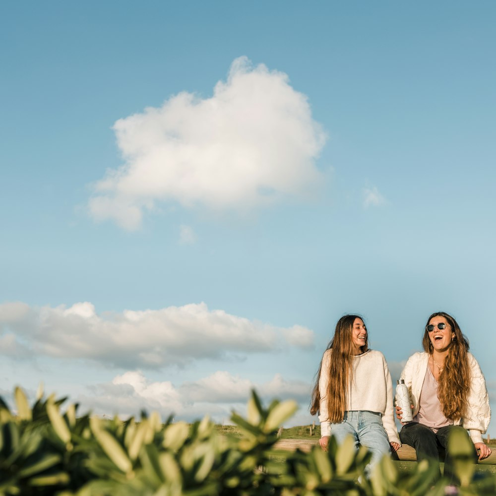 3 women standing on green grass field under blue sky during daytime
