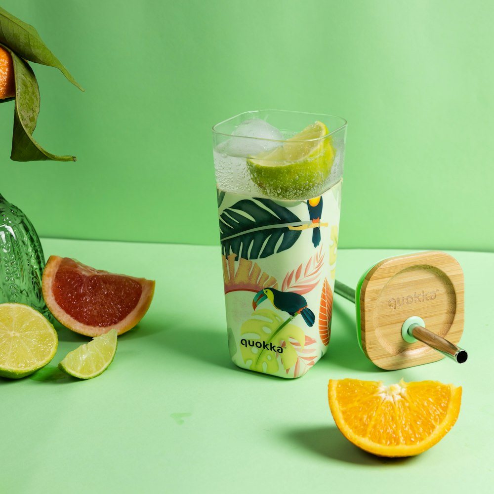 clear drinking glass with sliced lemon and green liquid