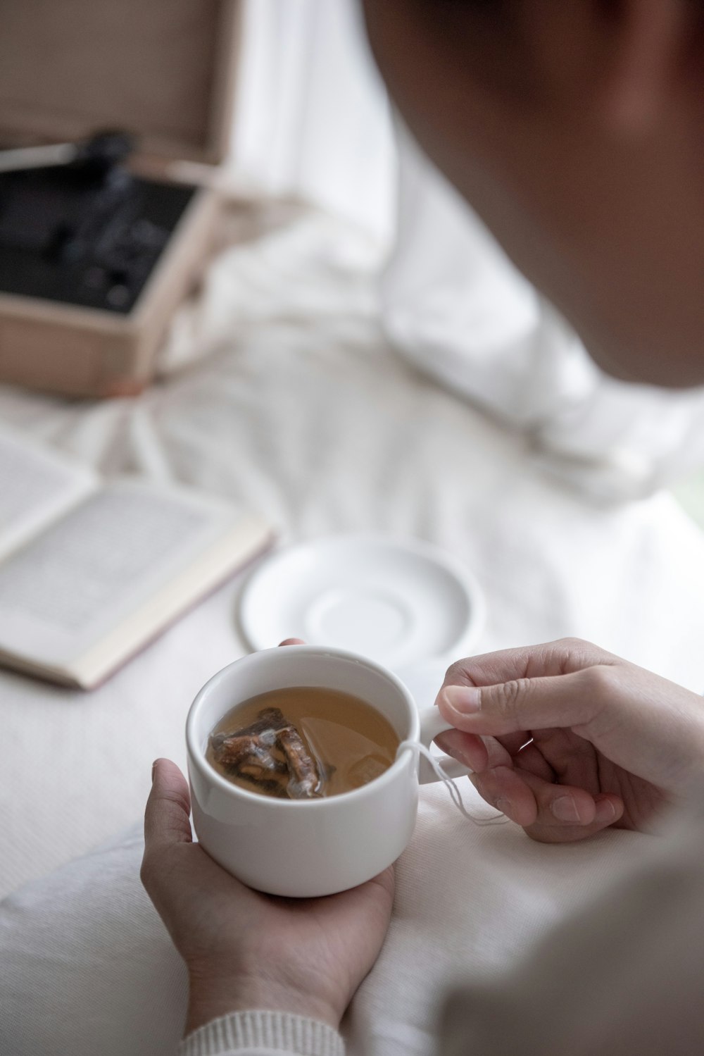 person holding white ceramic cup with brown liquid