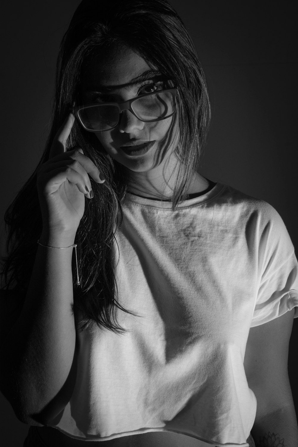 Femme en T-shirt à col rond blanc portant des lunettes à monture noire