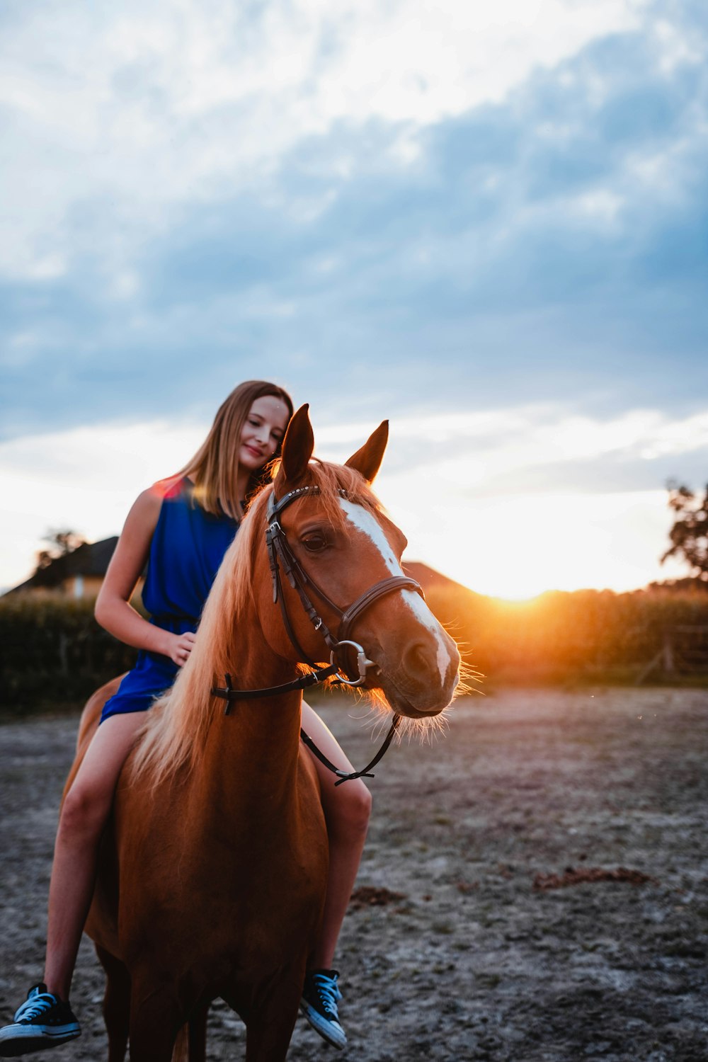 woman in blue shirt riding brown horse during daytime