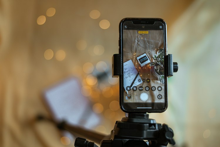 A person photographing a used item on a plain background with natural light from a window