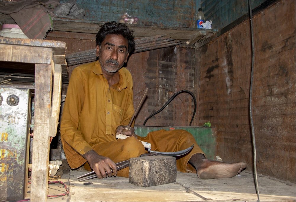 man in yellow long sleeve shirt holding brown wooden stick