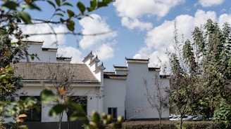 A charming traditional building in Malang surrounded by lush greenery under a bright blue sky.