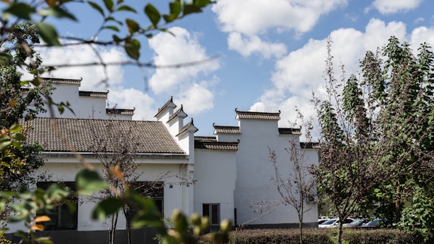 A charming traditional building in Malang surrounded by lush greenery under a bright blue sky.