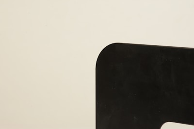 A minimalist image featuring a sharply defined black shape with rounded edges against a plain beige background. The shape occupies the right side, creating a stark contrast.