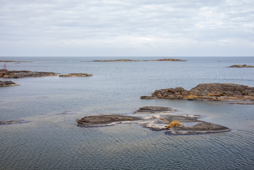 Formación de roca marrón en el mar bajo nubes blancas durante el día