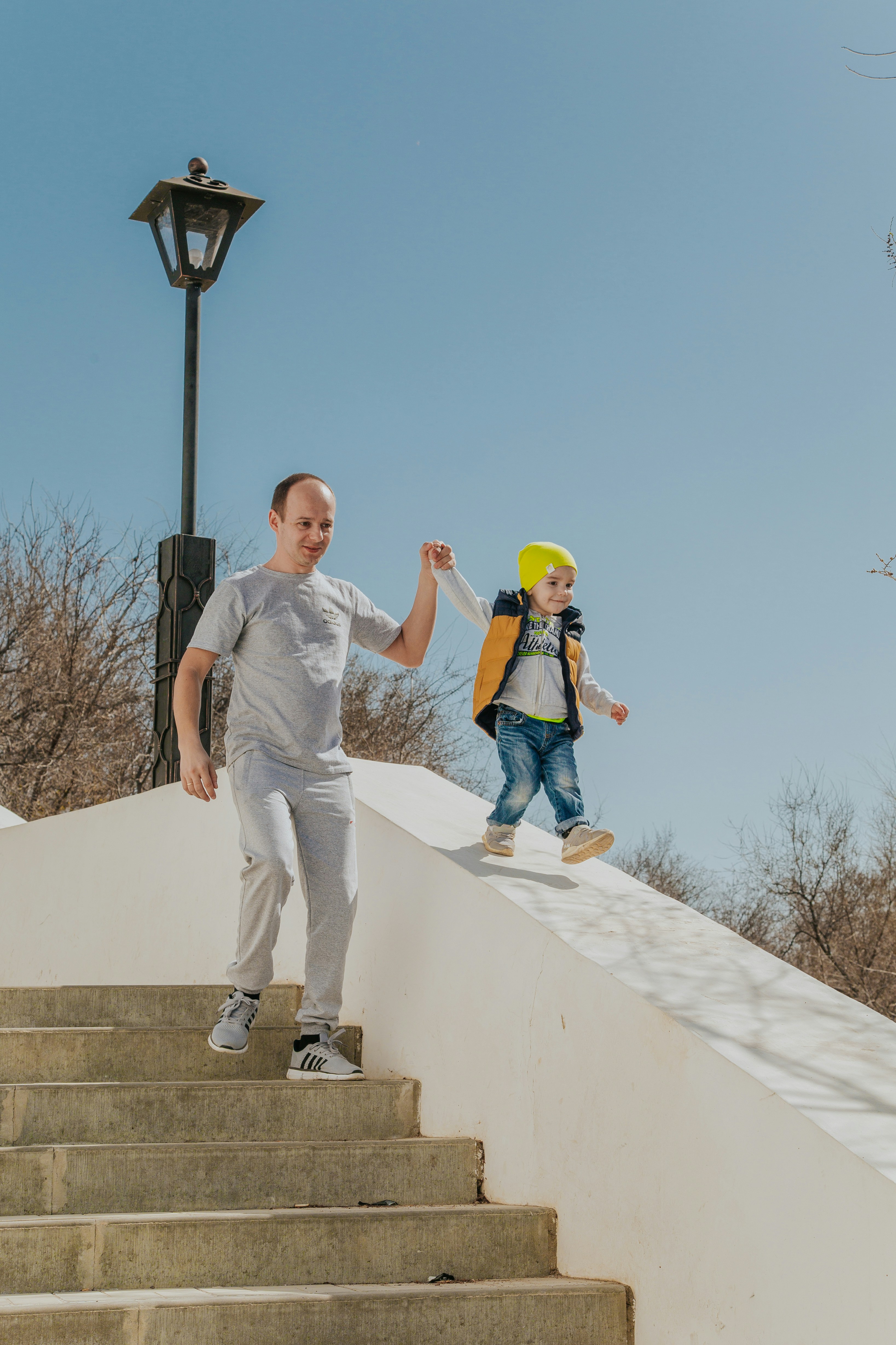 man in gray crew neck t-shirt and blue denim jeans standing on white concrete wall