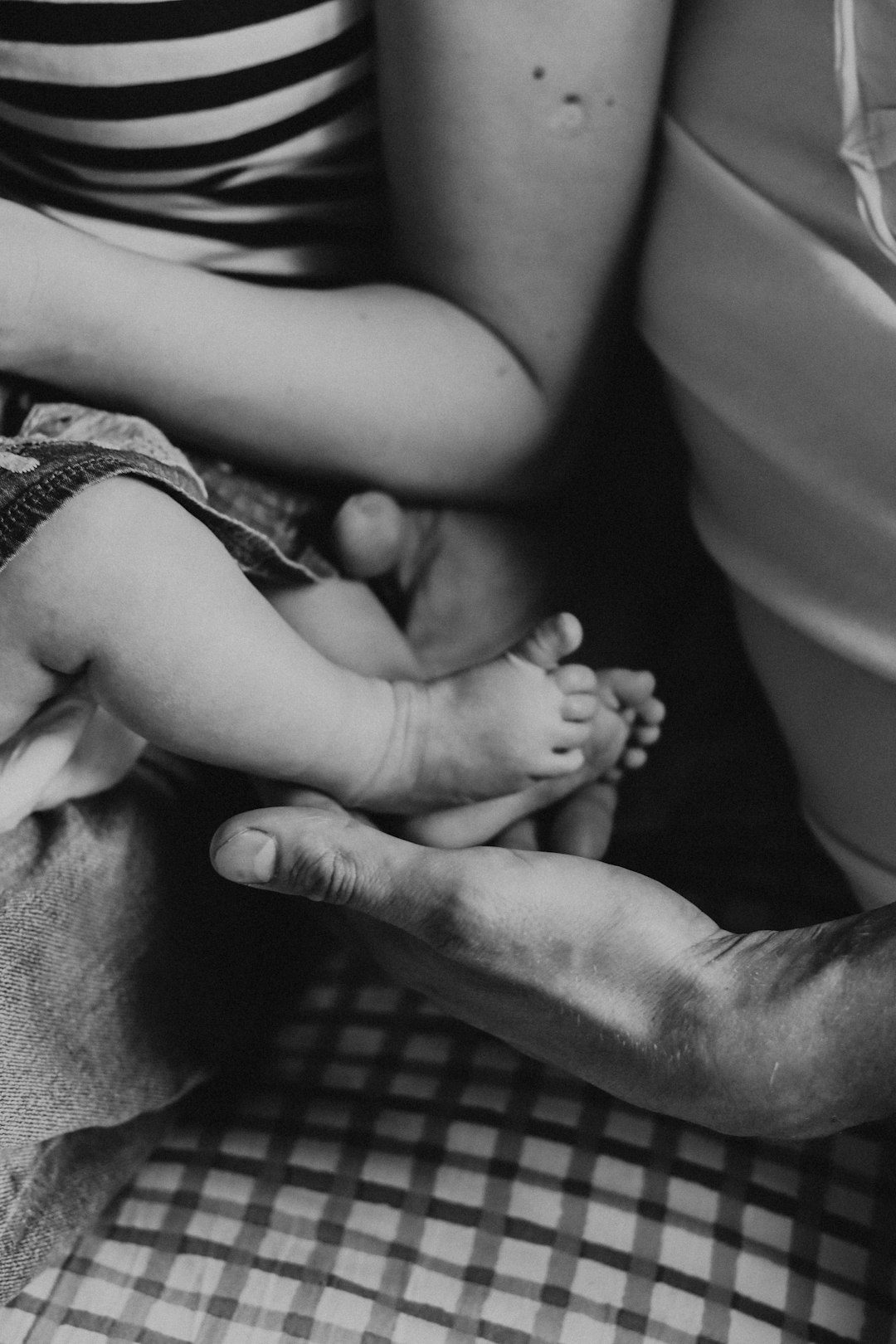 grayscale photo of man and woman holding their babys feet