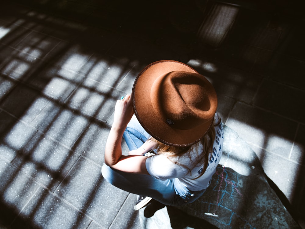 Donna in camicia a quadri blu e bianca e cappello Fedora marrone