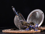 An elegant stainless steel tea infuser resting on a ceramic dish.