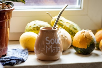brown ceramic jar with lid beside yellow round fruit