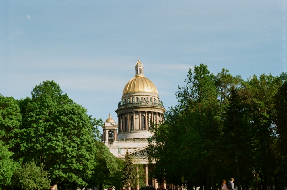 white and gold dome building surrounded by green trees under white sky during daytime
