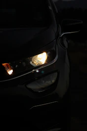 Close-up of a sleek car headlight glowing softly in twilight.