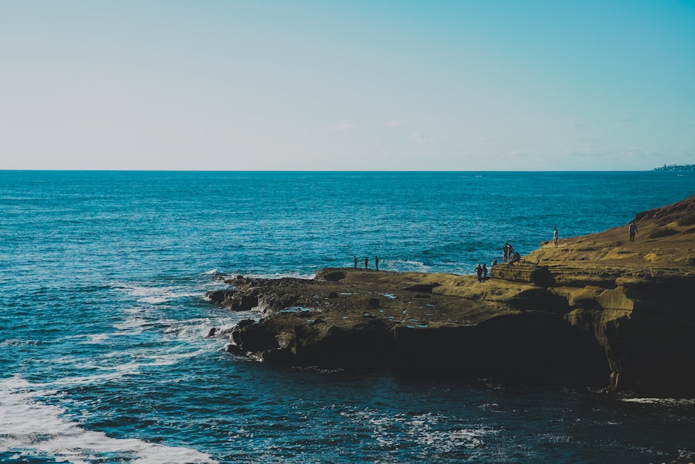 people standing on rock formation near sea during daytime