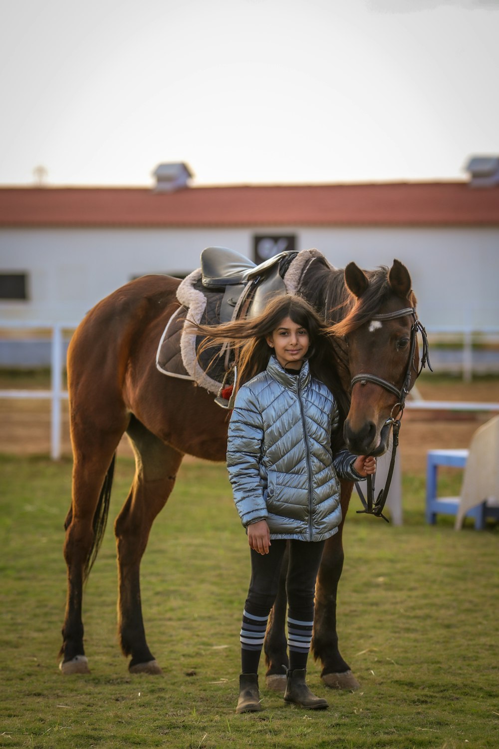 woman in blue denim jacket and blue denim jeans standing beside brown horse during daytime