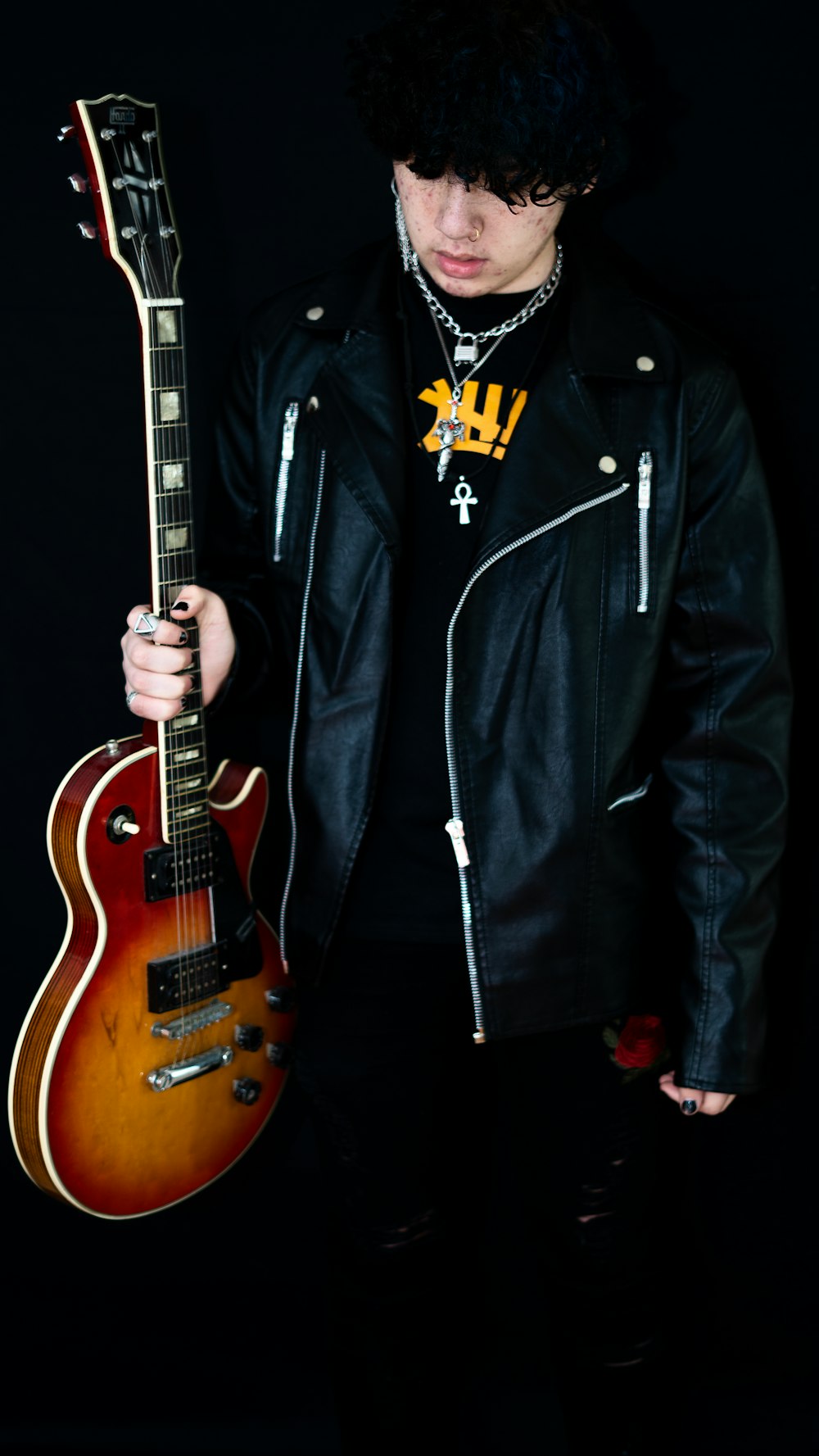 man in black zip up jacket holding brown electric guitar