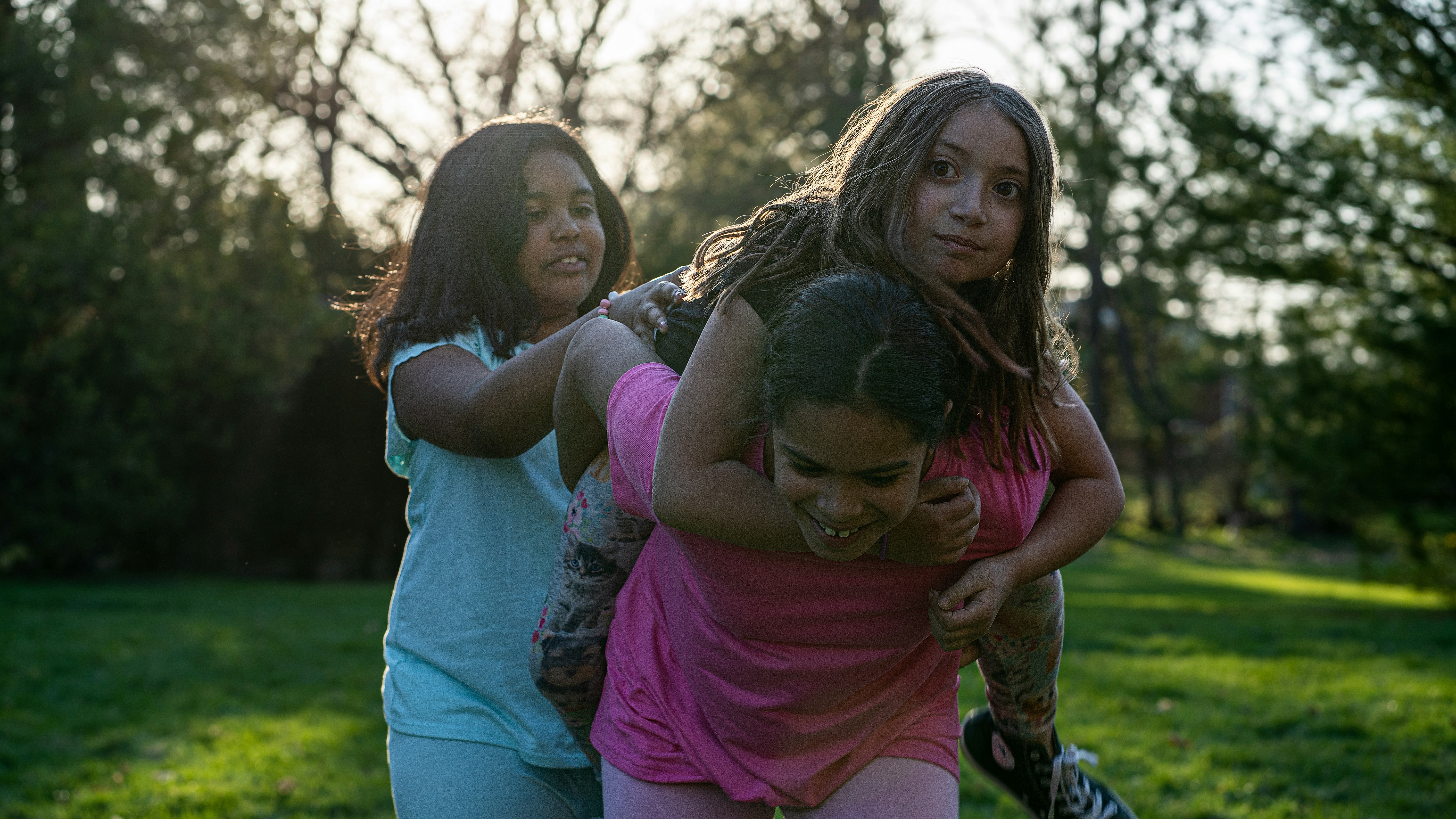 woman in pink shirt carrying girl in blue shirt