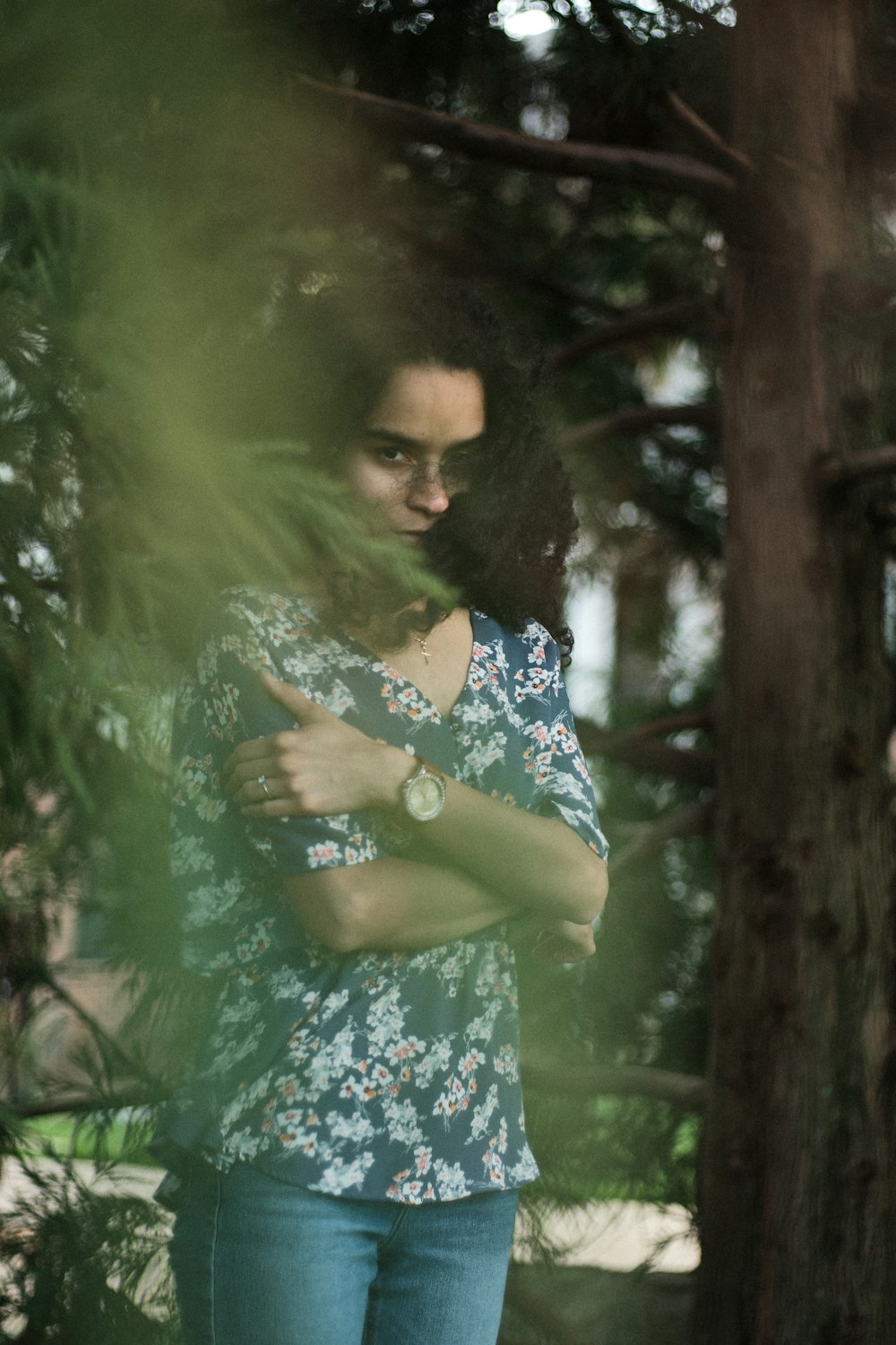 woman in blue and white floral dress standing beside green tree during daytime