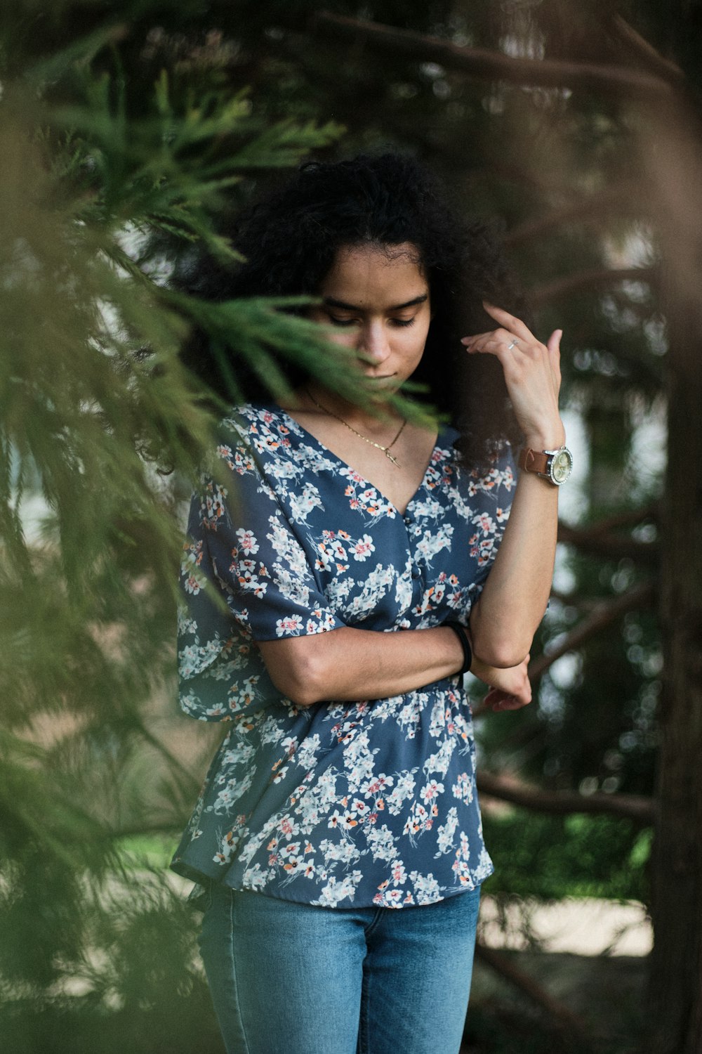 woman in blue and white floral dress standing near green tree