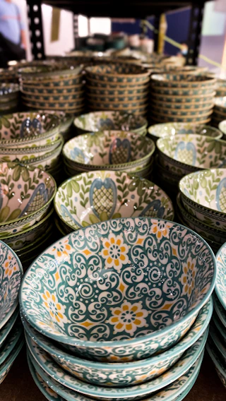 A vibrant display of hand-thrown stoneware bowls in bright blues and yellows, arranged on a cozy wooden shelf.