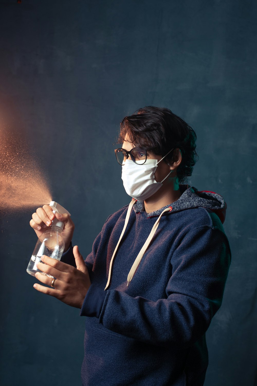 woman in blue jacket holding clear drinking glass