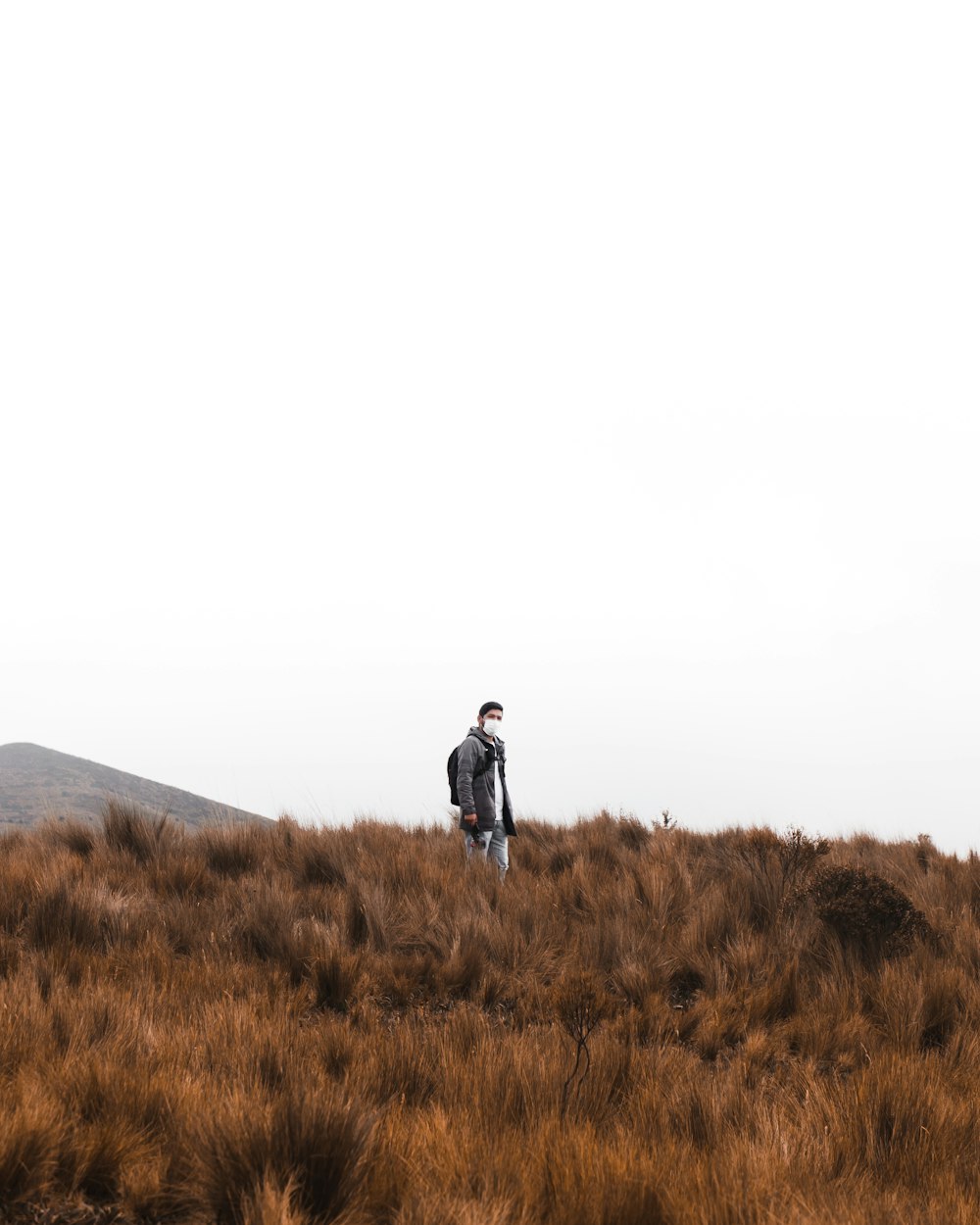 man in black jacket standing on brown grass field during daytime