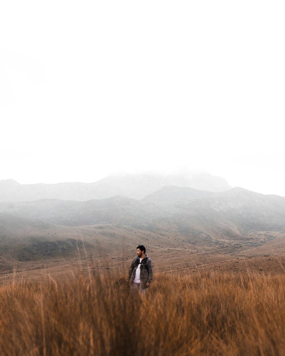 man in black jacket standing on brown grass field during daytime