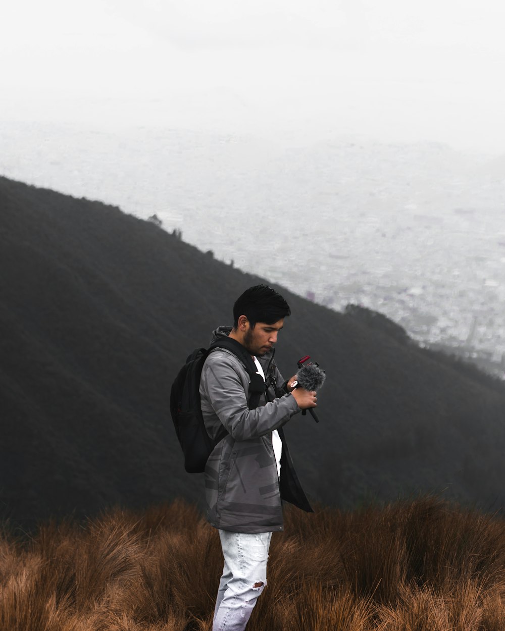 man in black jacket and white pants standing on brown grass field during daytime