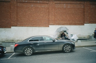 black coupe parked beside brown brick wall