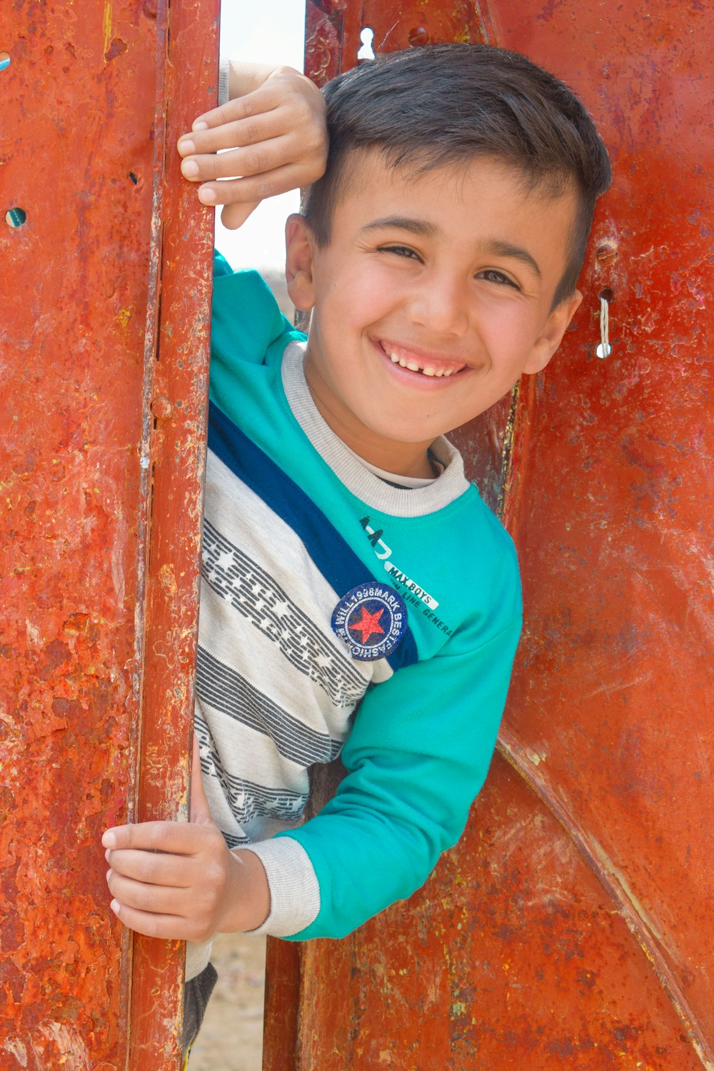 boy in red and blue long sleeve shirt smiling