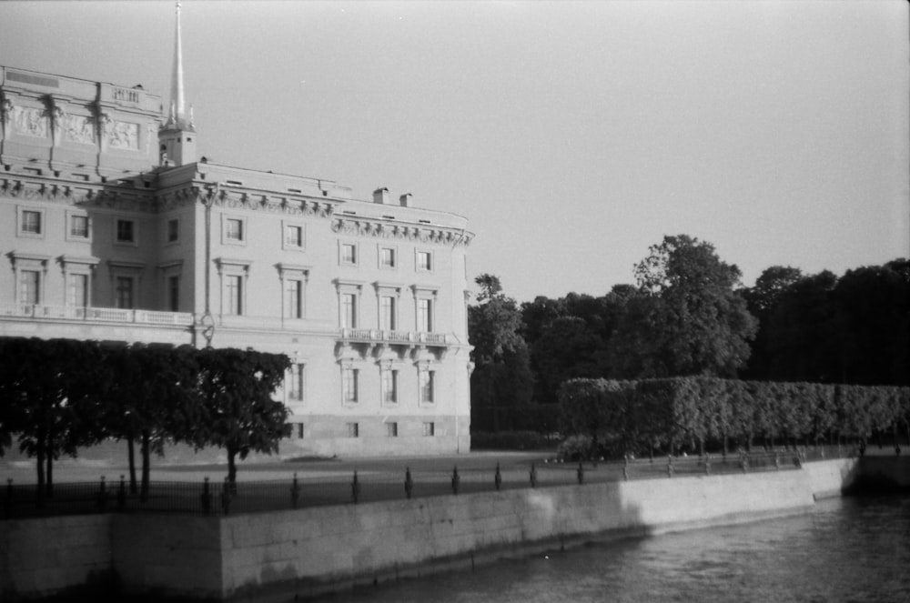 grayscale photo of concrete building near body of water