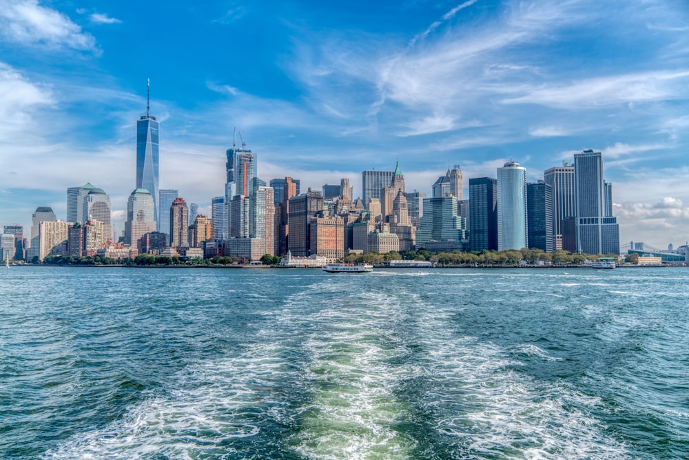 skyline della città attraverso lo specchio d'acqua sotto il cielo nuvoloso soleggiato blu e bianco durante il giorno