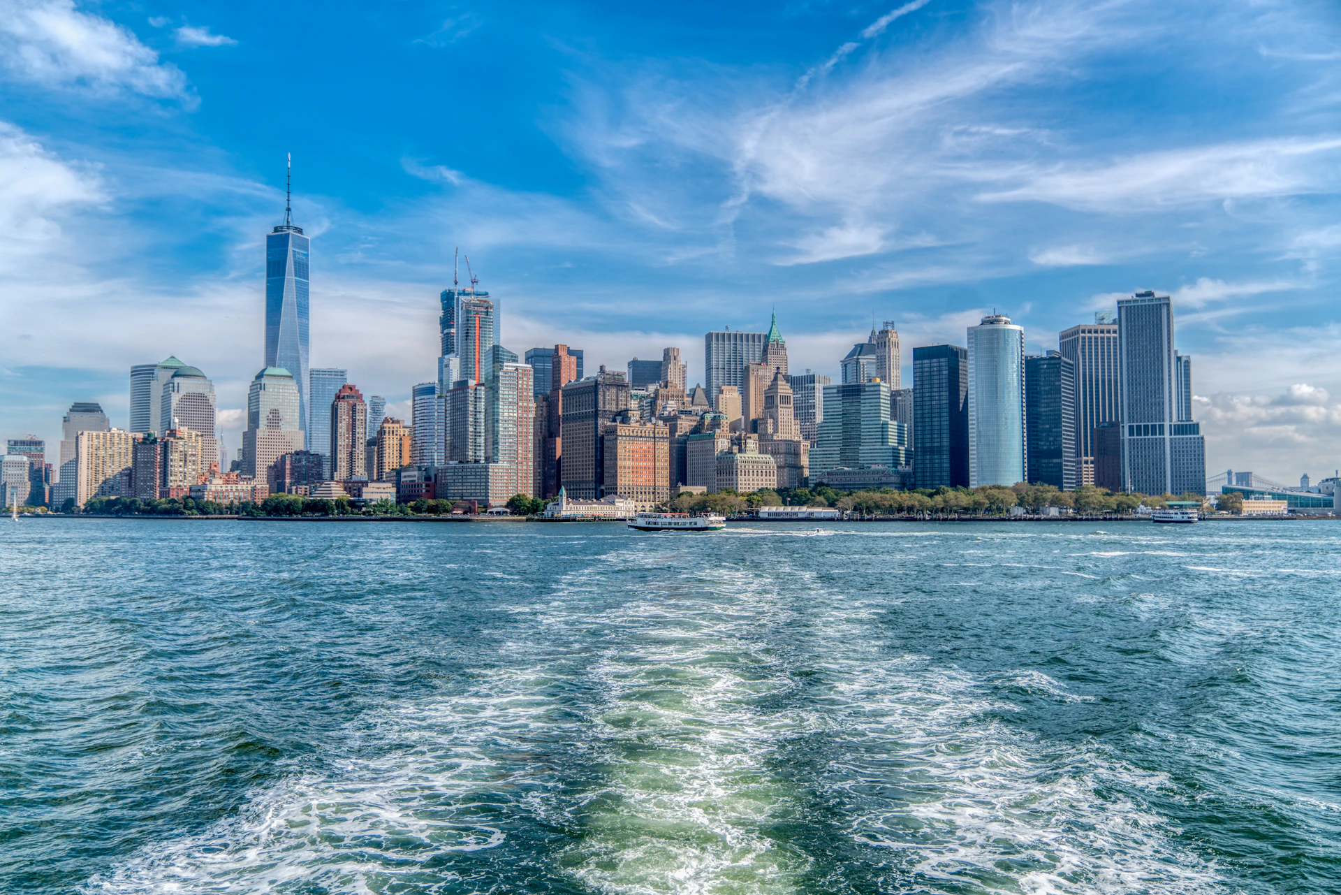 city skyline across body of water under blue and white sunny cloudy sky during daytime