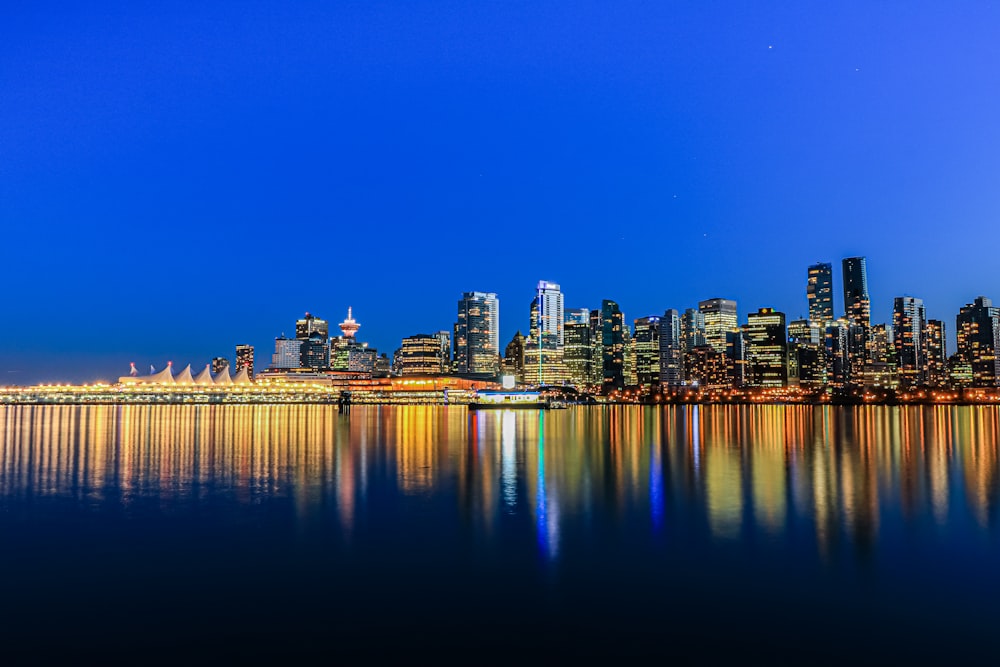 city skyline across body of water during night time